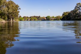 Photo of Rowville Lakes taken from water level with houses in background and trees on side banks