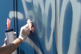 Hand cleaning graffiti off wall. 