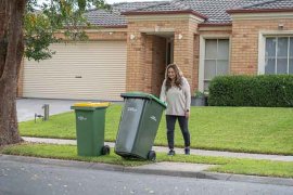lady putting out the green bin on the kerb