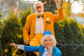 Two people outside, one wearing a orange suit and the second wearing a blue suit. 