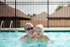 Woman and child in a pool with a safety barrier.