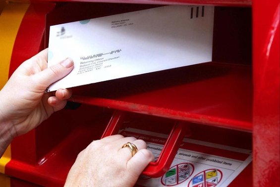 A person posting their ballot in a letterbox