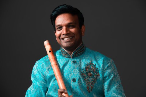 A man smiling and holding a flute