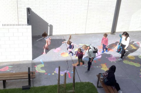 Children playing outside, with chalk drawings on the pavement