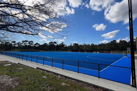 A blue hockey pitch surrounded by flood lights