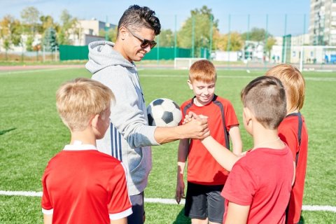 Soccer coach interacting with young soccer players