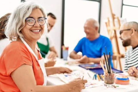 Group of adults sitting around a table painting and doing crafts