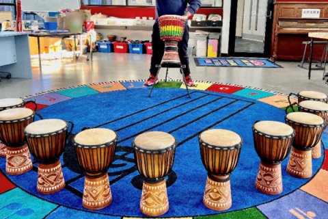 10 djembe drums in a circle on a colour mat