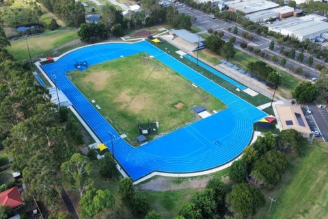 Aerial view of the new Knox Athletics track. It has blue track in an oval shape with grass in the middle, and multi-coloured shade sails.